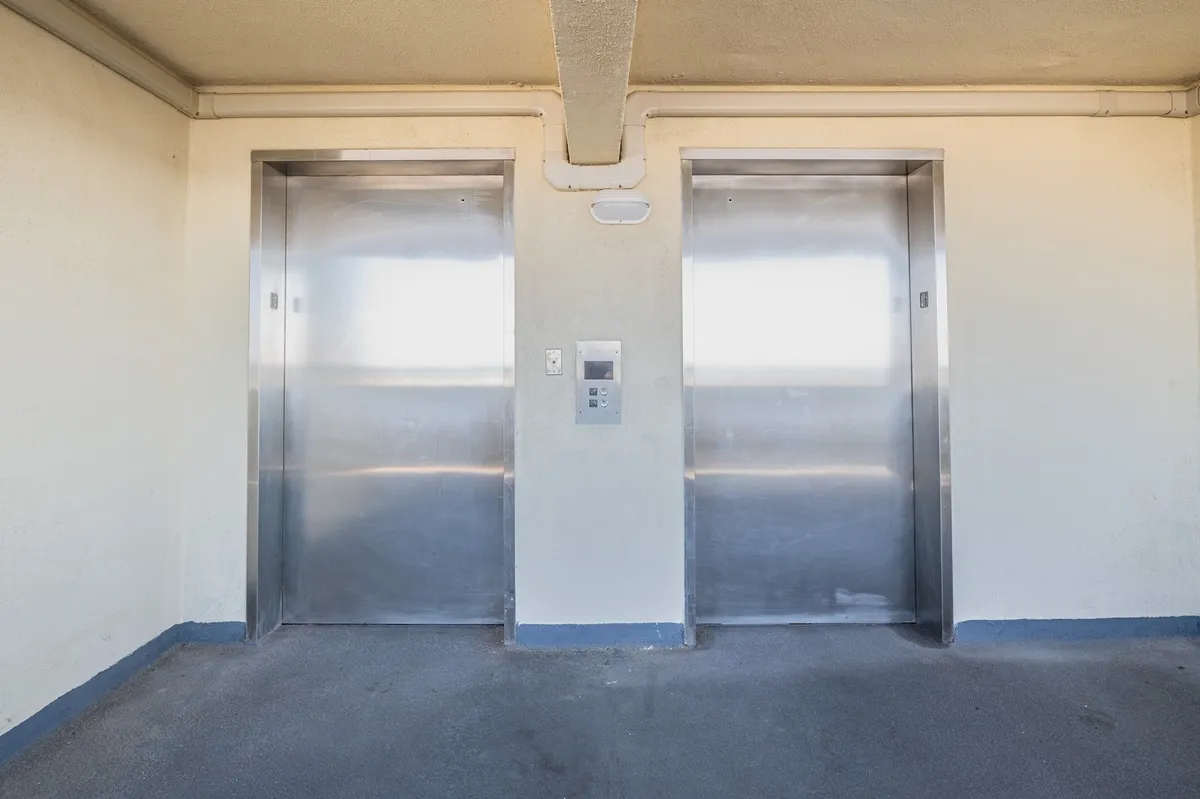 A bright and functional elevator lobby with modern elevators and a control panel, suggesting convenience and easy access throughout the building.