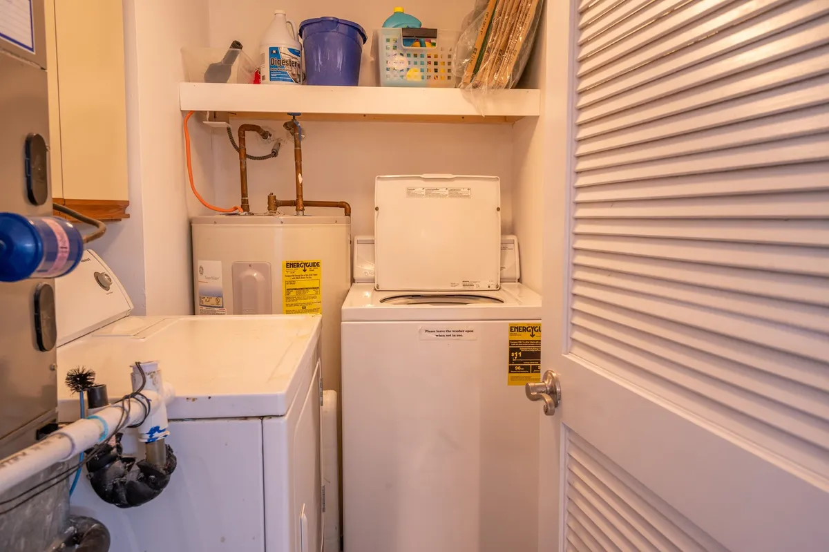 A practical laundry area with a washer, dryer, and organized storage shelves. The space is clean and efficient, emphasizing convenience for longer stays.